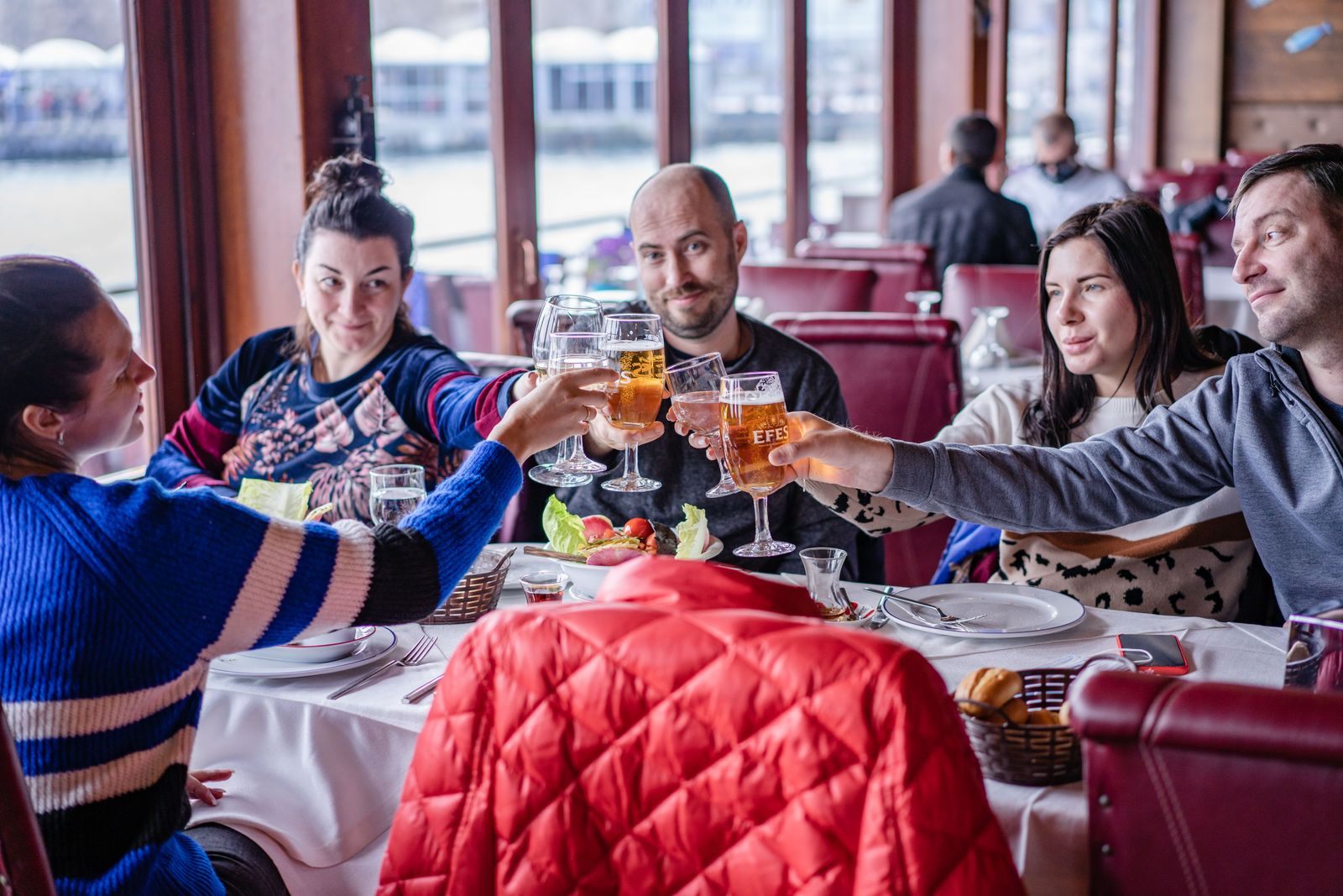Friends toasting around a restaurant table, the kind of group that asks how to book a group cruise on Carnival