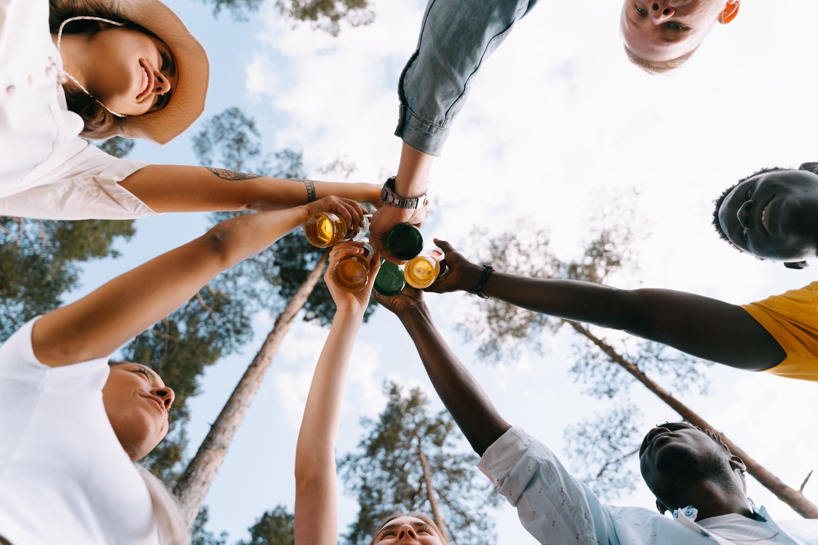 Circle of friends raising drinks together under a blue sky, celebrating one of their group cruise deals