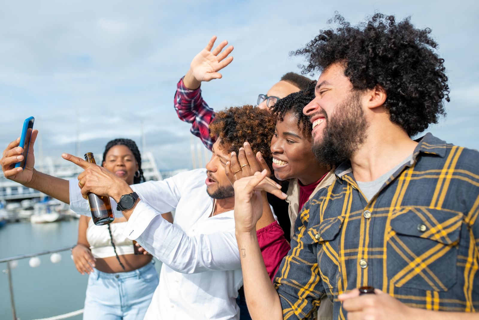 Friends taking a selfie on a boat in a sunny marina, planning how to book a group cruise on NCL