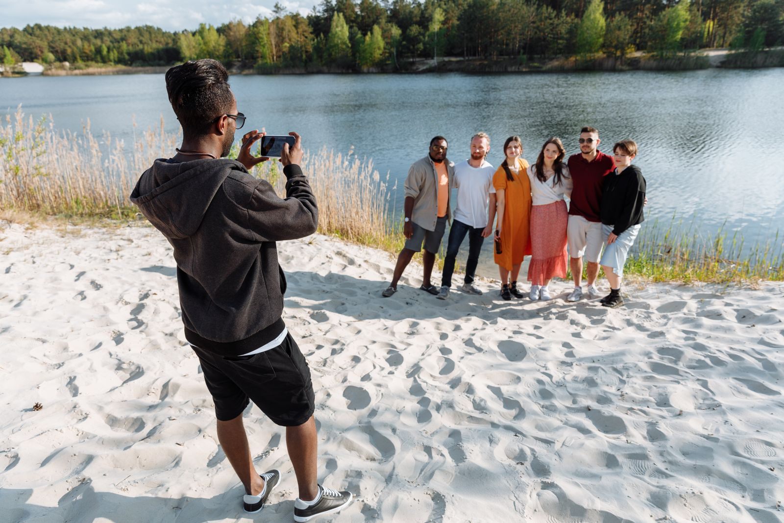 Group of friends lined up on a lakeside beach for a photo, wondering do cruises offer group rates