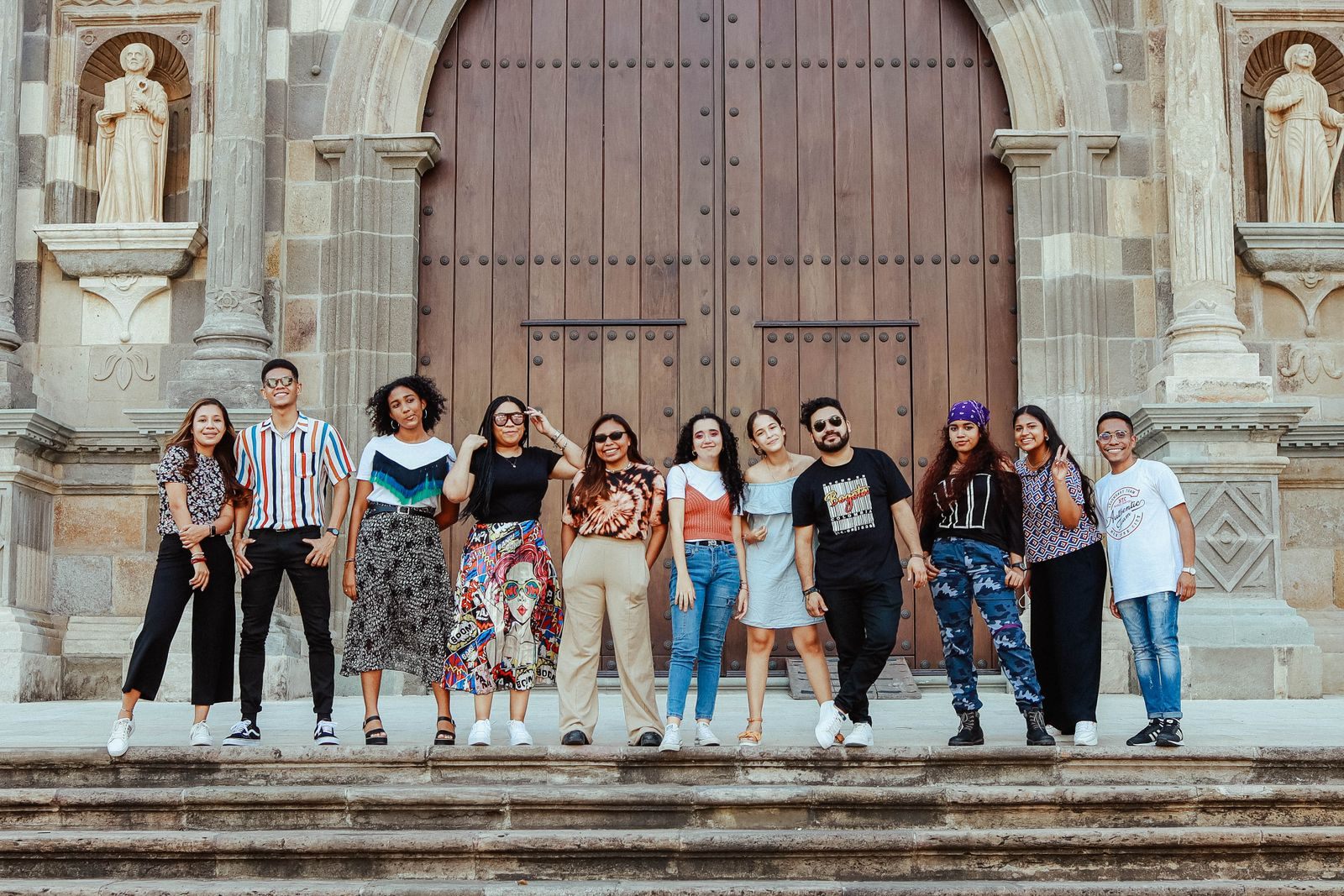 Large group of friends posing on the steps of a historic building before learning how to book a group cruise on Royal Caribbean