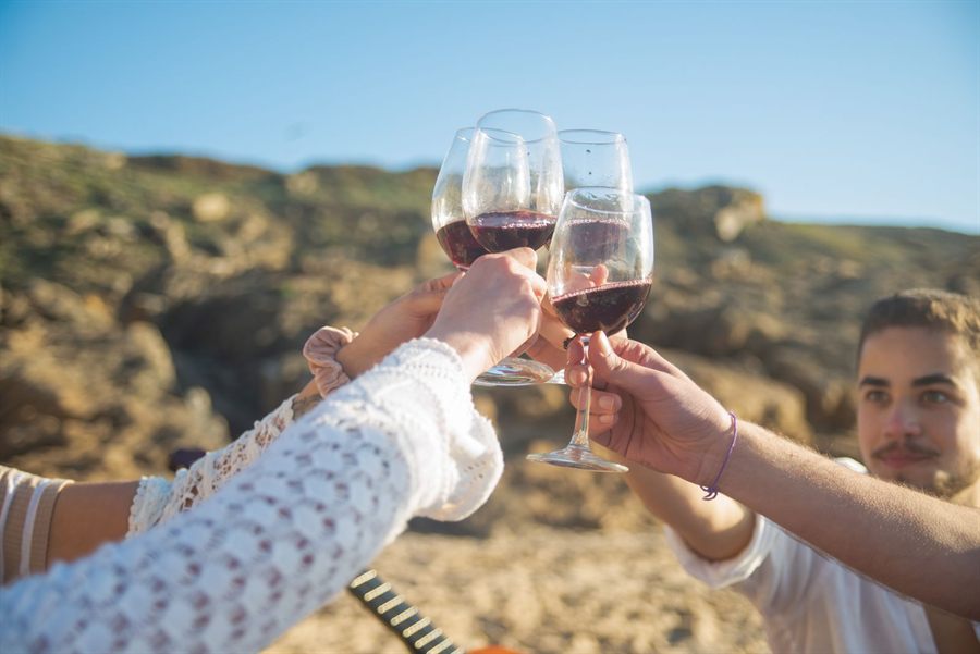 Friends clinking glasses of red wine outdoors